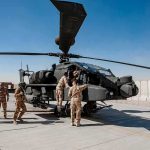 Hormuz Flashpoint: Will Trump Hit Back? Soldiers inspect a military attack helicopter on a tarmac