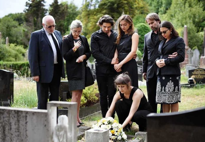 Mourners gathered at a graveside placing flowers