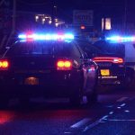 Motel Door Blown—The Paperwork’s Missing Police cars with flashing lights at a nighttime scene near a motel