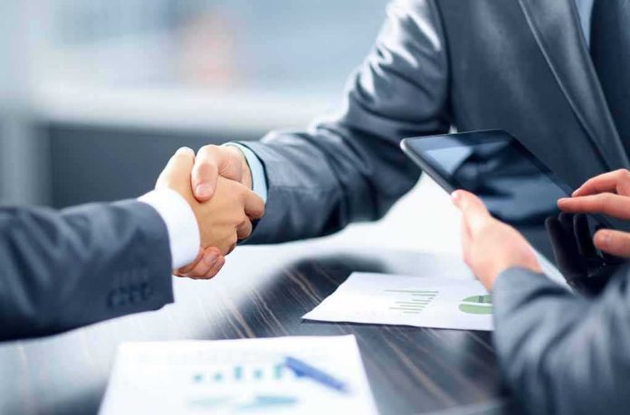 shutterstock_130099715 Businesspeople handshake at meeting table