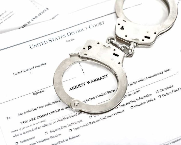 shutterstock_1316784506 Handcuffs on arrest warrant documents