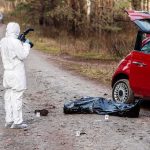AI Camera Sparks 13-Day Jail Nightmare forensic investigator photographing crime scene near red car on forest road