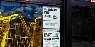 Yellow shopping carts beside store entrance with SNAP benefits sign