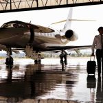 A Legendary American Pilot Reveals His Diagnosis Pilot walking with suitcase beside private jet in hangar