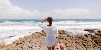 Families Stunned by Toxic Beach Crawler Woman in white cover-up standing on rocky shore by the ocean