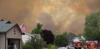 Emergency vehicles respond to wildfire near suburban homes