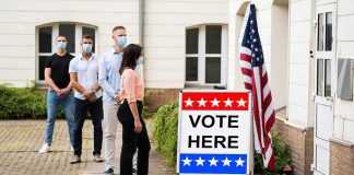 Nine Felonies: Voter Scam Stuns City Voters wearing masks line up outside a polling place