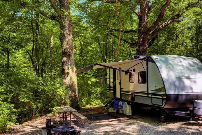 shutterstock_1780179764 travel trailer parked at a wooded campsite