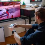 Netflix Nabs GTA VI First — What’s Missing? man playing video game on a TV with a controller