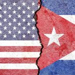 Blackout Spiral – Trump Turns The Screws Split wall showing USA and Cuba flags divided by a crack