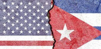 Blackout Spiral – Trump Turns The Screws Split wall showing USA and Cuba flags divided by a crack
