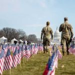 National Mall Threat Sparks Federal Hunt Two soldiers walk among American flags toward the U.S. Capitol