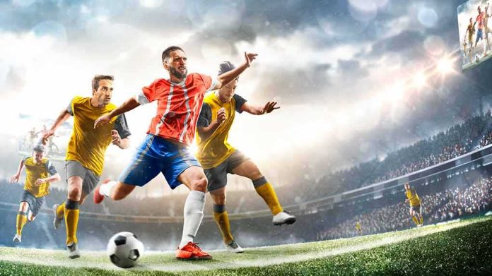 shutterstock_1992389864 Soccer player in red jersey kicking ball during match