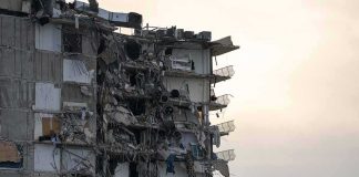 Partially collapsed apartment building with exposed rooms and debris