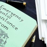 Notebook titled Emergency Rental Assistance Program beside papers and pen