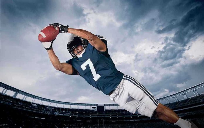 shutterstock_203972608 Akeel Lynch diving to catch a football in a stadium