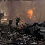 Firefighters tackle blaze amid rubble and a burned car