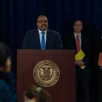 Trespass Twist: Diversion Or Celebrity Pass? Man at podium during press conference with officials behind him