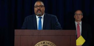 Man speaks at podium with New York County District Attorney seal