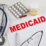 Medicaid document with stethoscope and medications on desk