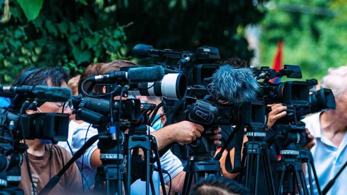shutterstock_2210577723-1 TV news cameras crowding together at an outdoor event