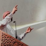 Mayor’s Holiday Bet Ignites Constitutional Clash Speaker in traditional attire gesturing from a carved wooden podium