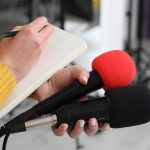 Unseen Killer: The Stone Dust Crisis! Journalist holding two microphones while writing in a notebook