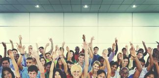 Group of people raising hands in an indoor audience
