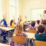 Expelled for Voting Trump in a Mock Election — Mother Makes Serious Claim Students raise hands in a classroom with a teacher at the front