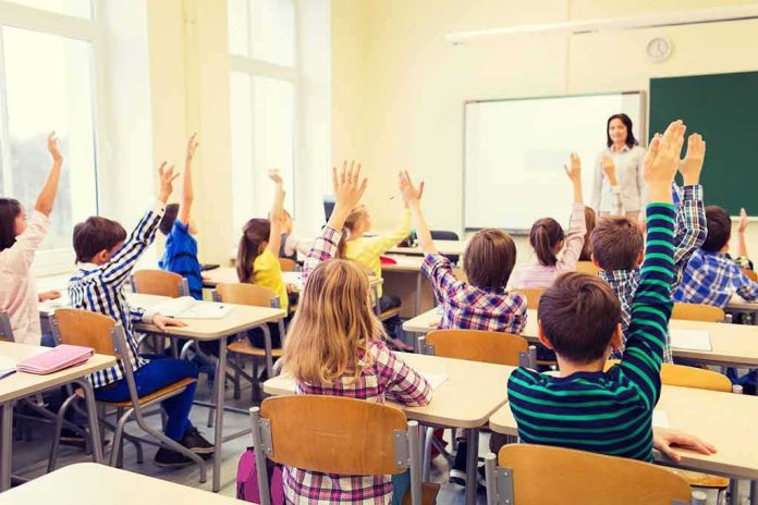 shutterstock_326638589 Students raise hands in a classroom with a teacher at the front