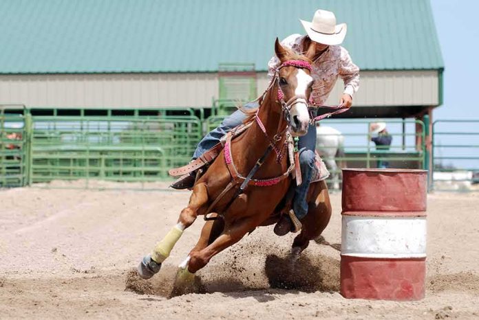 shutterstock_351924605 Barrel racer guiding a horse around a barrel in an arena