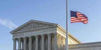 United States Supreme Court building with flag at half-staff