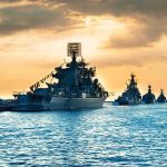 Hormuz Stalls Again — Prices Next? Naval warships anchored in a harbor at sunset