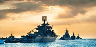 Naval warships anchored in a harbor at sunset