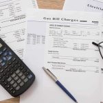 The Experiment That Began During The 2008 Crisis Utility bills with calculator, pen, and eyeglasses on a desk