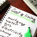 America Keeps Hiring But Growth Feels Mixed Budget notebook with cost of living list, calculator, and cash