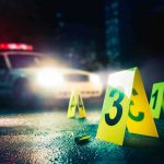 Chaos Erupts: Suspect Still Loose crime scene markers on wet street with police car lights