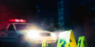 crime scene markers on wet street with police car lights