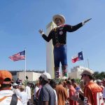 Giant cowboy statue towers over a crowd at an outdoor event