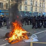 Fire burning on the street amid police presence.