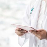 Fake Doctor Pushed Surgeries – Massive Bust Doctor with stethoscope using a tablet