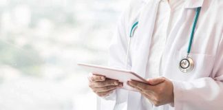 Fake Doctor Pushed Surgeries – Massive Bust Doctor with stethoscope using a tablet