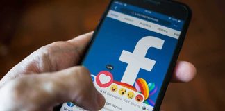 Engagement Jackpot, Safety Meltdown at Meta Hand using smartphone with Facebook reactions on screen