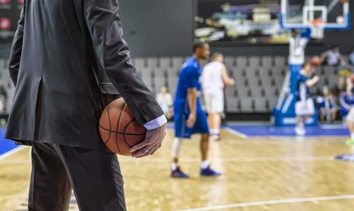 shutterstock_1089242369 Basketball coach in suit holding ball courtside