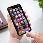 Person using a smartphone with apps on the home screen