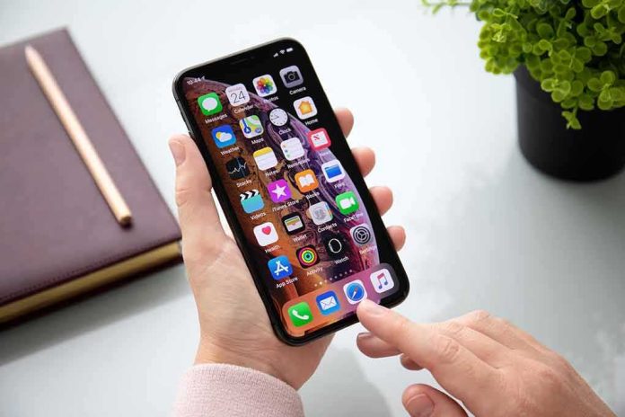shutterstock_1191439213 Person using a smartphone with apps on the home screen