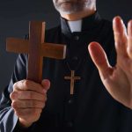 Mobilization Chaos Grabs Priest At Checkpoint Clergyman holding wooden cross with hand raised