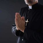 Founder Exposed: Moral Certainty Reached Clergyman in black robe praying with hands together