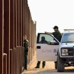 Billion-Dollar Border Plan Stalled Border patrol agents near a tall fence and a marked pickup truck