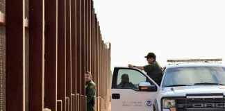 Billion-Dollar Border Plan Stalled Border patrol agents near a tall fence and a marked pickup truck